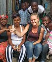 En pige fra et dansk universitet sidder sammen med en gruppe smilende, lokale mennesker i Kenya. Foto: Nordea-fonden