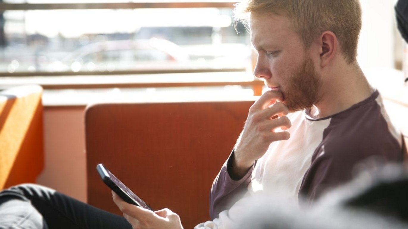 Billede af person siddende med mobiltelefon