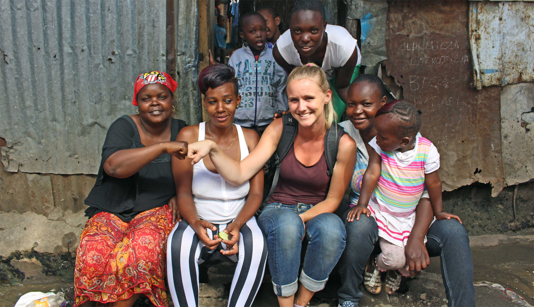 En pige fra et dansk universitet sidder sammen med en gruppe smilende, lokale mennesker i Kenya. Foto: Nordea-fonden